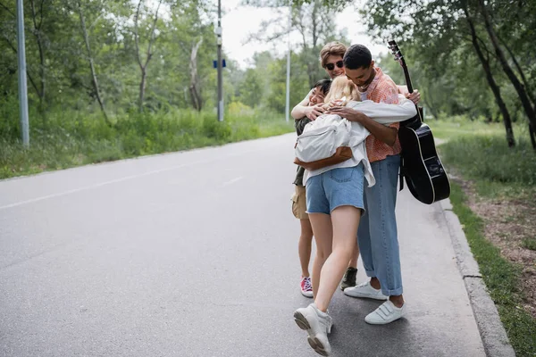 Happy multiethnic travelers embracing on countryside road — Stockfoto