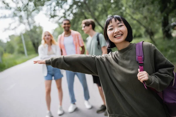 Happy asian woman stopping car near young multiethnic friends on blurred background — Fotografia de Stock