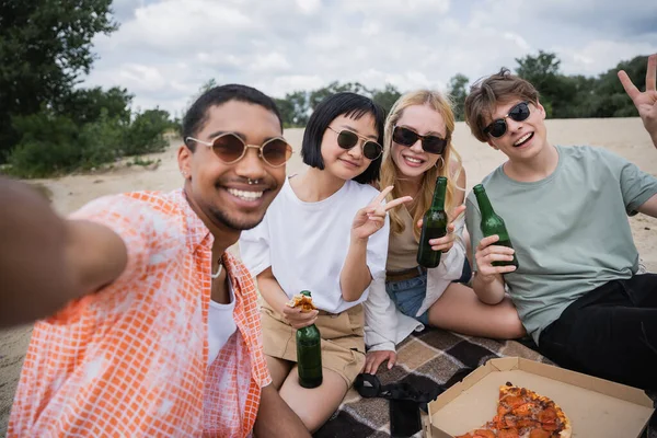 Happy multiethnic friends looking at camera and showing peace signs during beach party — Fotografia de Stock