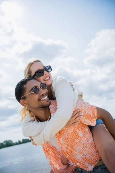 Happy african american man piggybacking girlfriend while looking away — Stock Photo