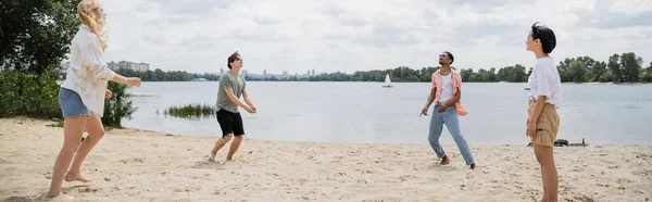 Young interracial people playing game on sand beach near river, banner - foto de stock