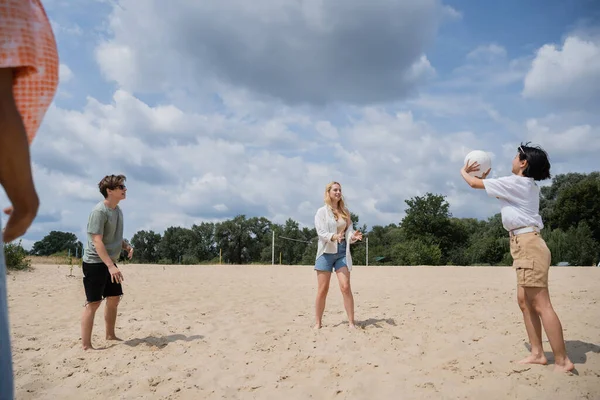 Young multiethnic friends playing volleyball on sand beach in summer - foto de stock