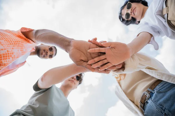 Bottom view of interracial men and women joining hands — Stock Photo