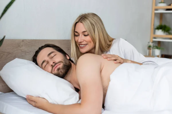 Happy blonde woman waking sleeping lover in morning — Stock Photo