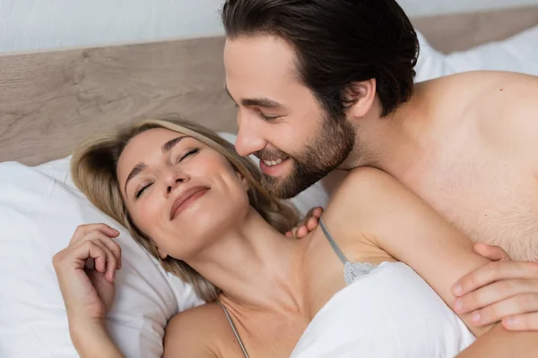 Smiling unshaven man waking happy blonde woman in morning — Stock Photo