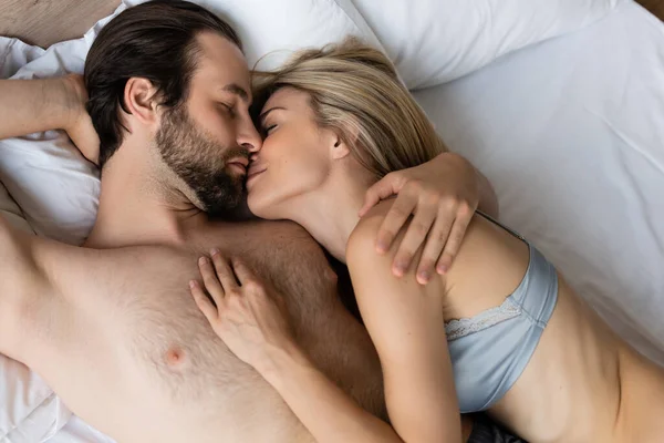 Вид зверху сексуальна пара обіймає і цілує із закритими очима на ліжку — стокове фото