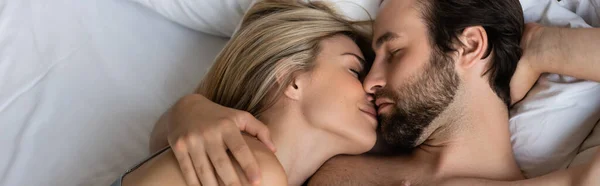 Top view of couple in love kissing with closed eyes on bed, banner — Stock Photo