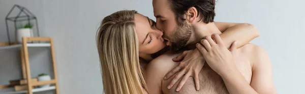 Sexy blonde woman with closed eyes kissing shirtless man at home, banner — Stock Photo