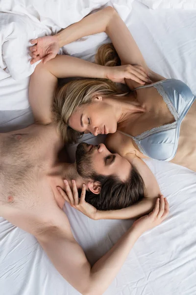 Вид зверху сорочки безнебезпечний чоловік і блондинка в бюстгальтері лежить обличчям до обличчя з закритими очима — стокове фото