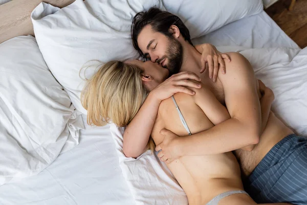 Top view of passionate couple lying on bed and embracing with closed eyes — Fotografia de Stock