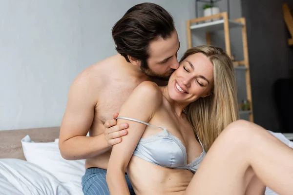 Брюнетка без сорочки чоловік цілує сексуальну і щасливу жінку, знімаючи її бюстгальтер — стокове фото