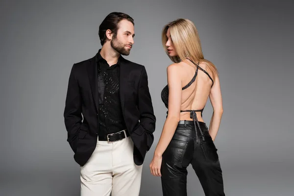 Stylish woman in leather pants standing near boyfriend isolated on grey — Stock Photo
