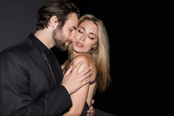 Bearded man touching sensual blonde girlfriend on dark background — Fotografia de Stock
