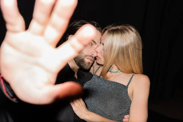 Young man covering camera while hugging blonde girlfriend isolated on black — Photo de stock