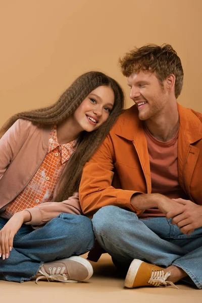 Cheerful girl leaning on shoulder of happy boyfriend isolated on beige — Stockfoto