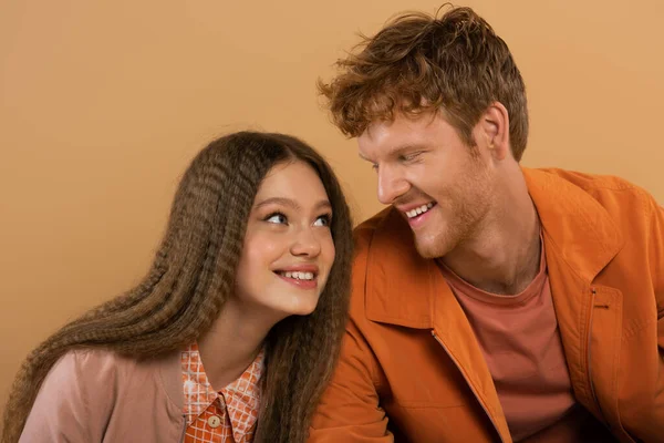 Cheerful girl smiling while looking at happy boyfriend isolated on beige — Stock Photo