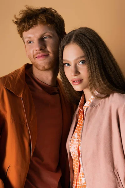 Smiling young man with red hair looking away near pretty girl isolated on beige — Foto stock