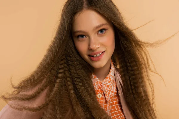 Cheerful teenage girl looking at camera while posing isolated on beige — Stockfoto