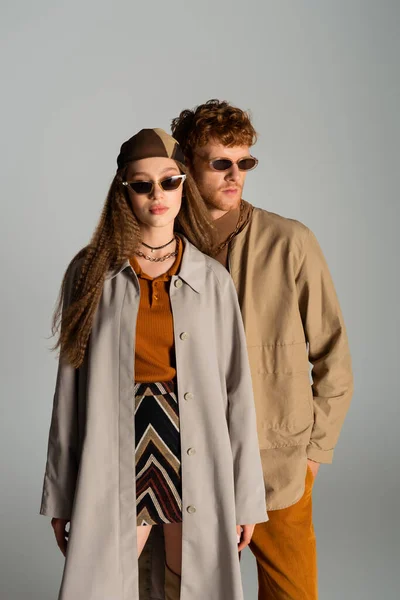 Young and stylish couple in autumnal outfits posing isolated on grey — Stock Photo