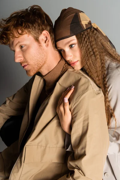 Teenage girl with wavy hair hugging redhead boyfriend on grey — Stock Photo