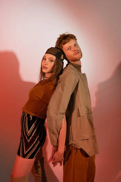 Teenage girl in headscarf and skirt standing back to back with boyfriend on red — Stock Photo