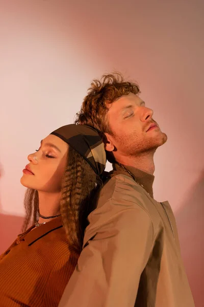 Teenage girl with closed eyes standing back to back with boyfriend on red - foto de stock