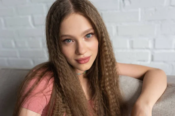 Portrait of pretty teenage girl in casual clothes sitting on couch in modern living room — Stock Photo