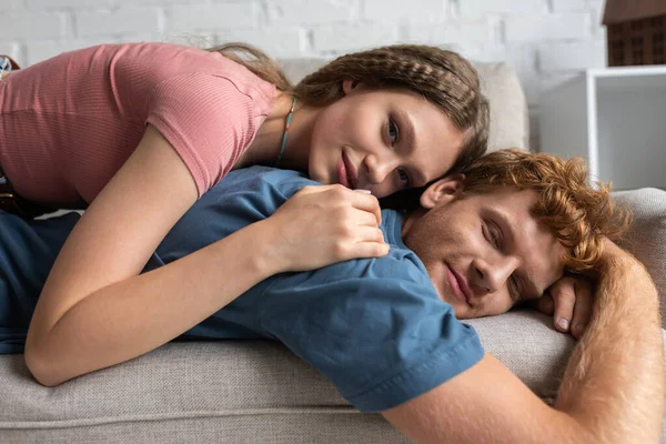Happy teenage girl lying on back of smiling boyfriend and resting on couch — Fotografia de Stock