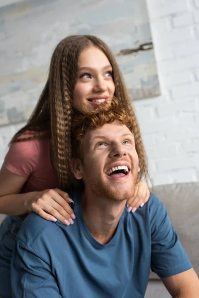 Happy teen girl smiling and hugging excited boyfriend in living room - foto de stock
