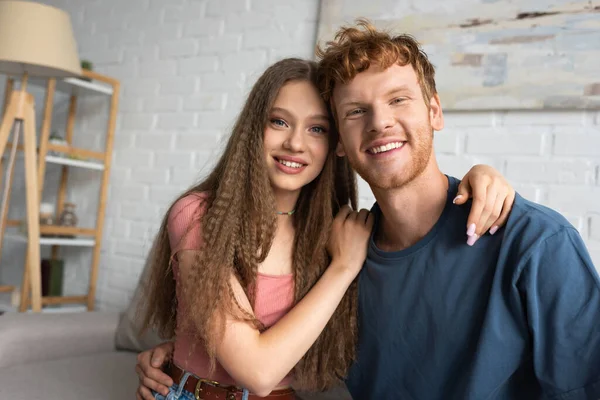 Happy and young man and cheerful girlfriend smiling while looking at camera — Stock Photo