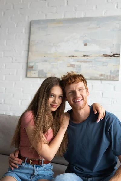 Joyful and young man and cheerful girlfriend smiling while looking at camera - foto de stock