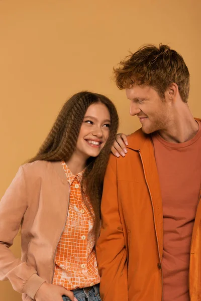 Happy young couple in autumnal outfits smiling together isolated on beige — стоковое фото