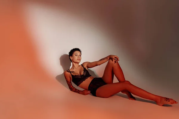 Piena lunghezza della donna appassionata in biancheria intima nera su sfondo rosso pallido con ombra — Foto stock