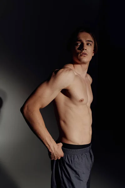 Young man with muscular torso looking away on black and grey background — Stock Photo