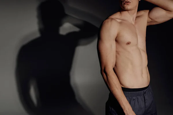 Cropped view of shirtless man with muscular body on grey background with black shadow — Stock Photo