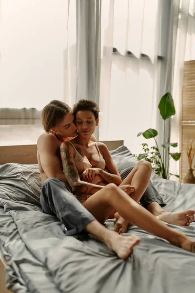 Jovem muscular homem beijando namorada no sutiã de renda na cama de manhã — Fotografia de Stock