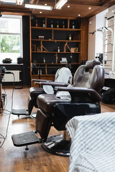 Poltronas ergonômicas e capas de cabeleireiro na barbearia contemporânea — Fotografia de Stock