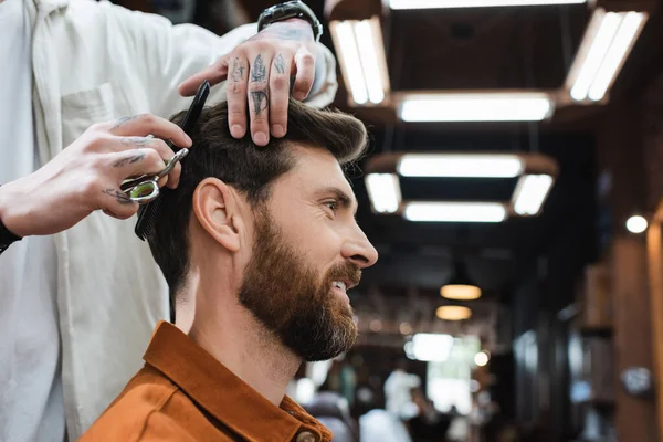 Cabeleireiro corte cabelo de morena barbuda homem sorrindo na barbearia — Fotografia de Stock