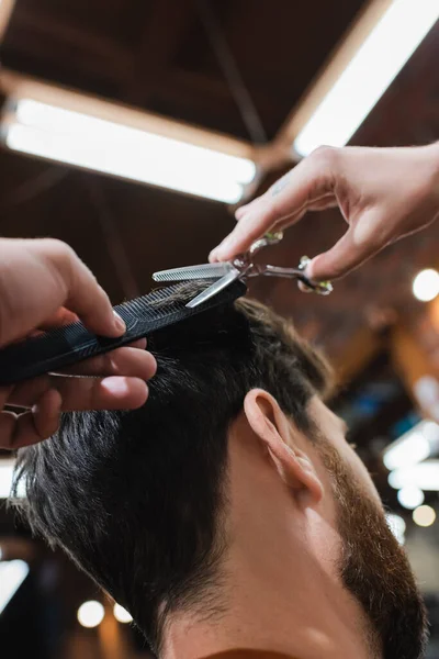 Hairdresser cutting hair of brunette man with thinning scissors — Stock Photo