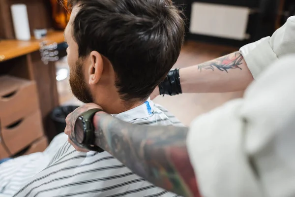 Brouillé coiffeur mettre coiffure cape sur brune homme — Photo de stock