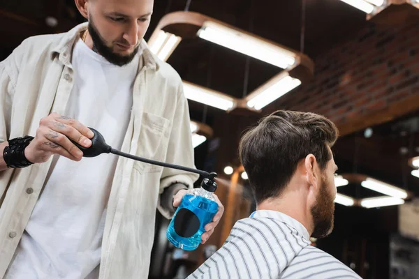 Bajo ángulo de vista del estilista rociando perfume en el cliente en la barbería — Stock Photo
