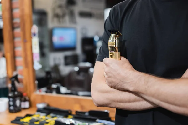 Vue recadrée du coiffeur tenant tondeuse à cheveux dans le salon de coiffure — Photo de stock