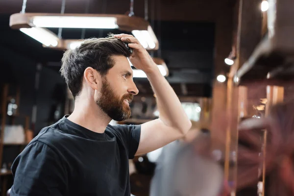 Боковой вид счастливой брюнетки мужчина трогает волосы в парикмахерской — стоковое фото