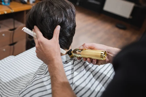Estilista recorte cuello de cliente con cortador de pelo en salón de belleza - foto de stock