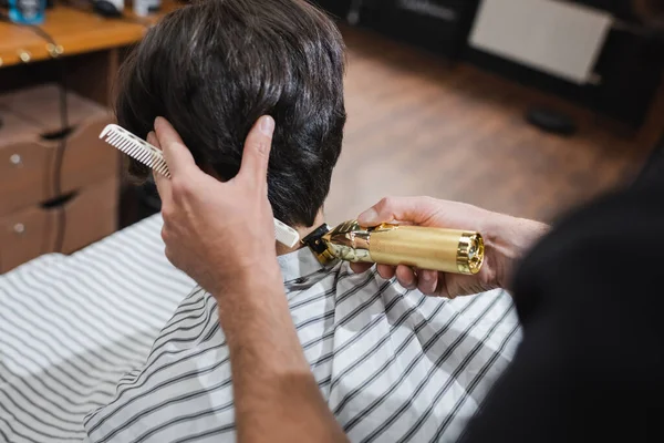 Hairstylist trimming neck of client with hair clipper in beauty salon — Stock Photo