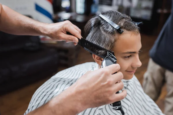 Peluquería recortar el cabello de cliente adolescente con cortador de pelo eléctrico - foto de stock