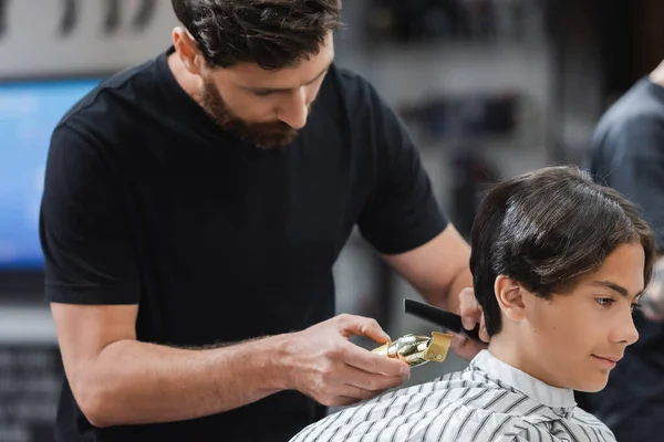 Friseur mit Haarschneidemaschine und Kamm in Kundennähe in Umhang im Schönheitssalon — Stockfoto