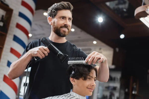 Positive Friseur Kämmen und Trocknen der Haare von Jugendlichen in Schönheitssalon — Stockfoto