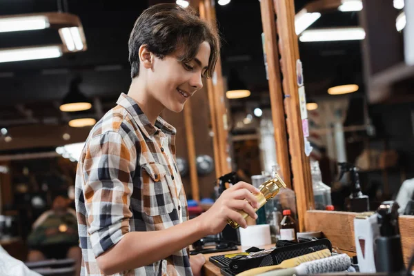 Fröhlicher Teenager mit Haarschneidemaschine in der Nähe von Kämmen und Kämmen im Schönheitssalon — Stockfoto