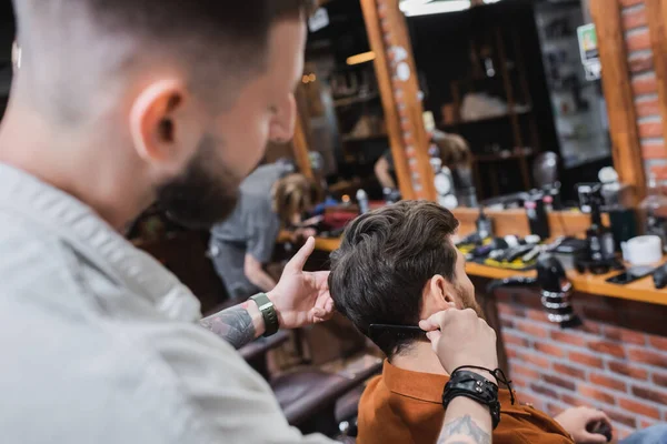 Cabeleireiro desfocado pentear o cabelo do homem no salão de beleza — Fotografia de Stock